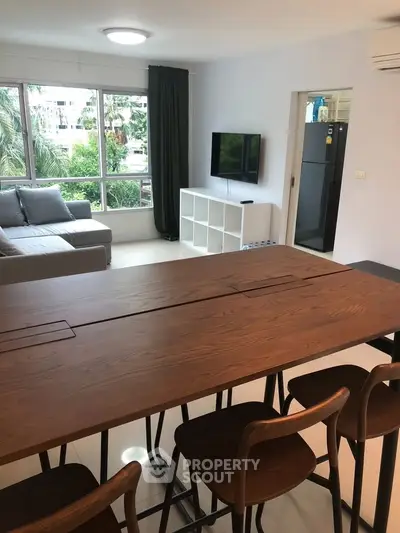Modern living room with sleek furniture and large windows offering lush garden views.