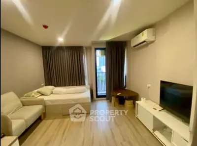 Modern studio apartment with cozy living area and balcony access, featuring sleek furniture and natural light.