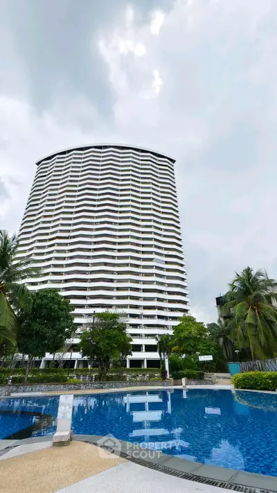 Stunning high-rise building with pool and lush greenery, perfect for luxury living.