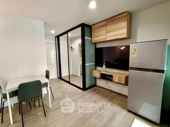 Modern apartment interior with sleek kitchen and dining area, featuring a stylish fridge and TV setup.