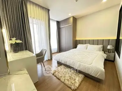 Elegant bedroom with modern decor, plush rug, and ample natural light.