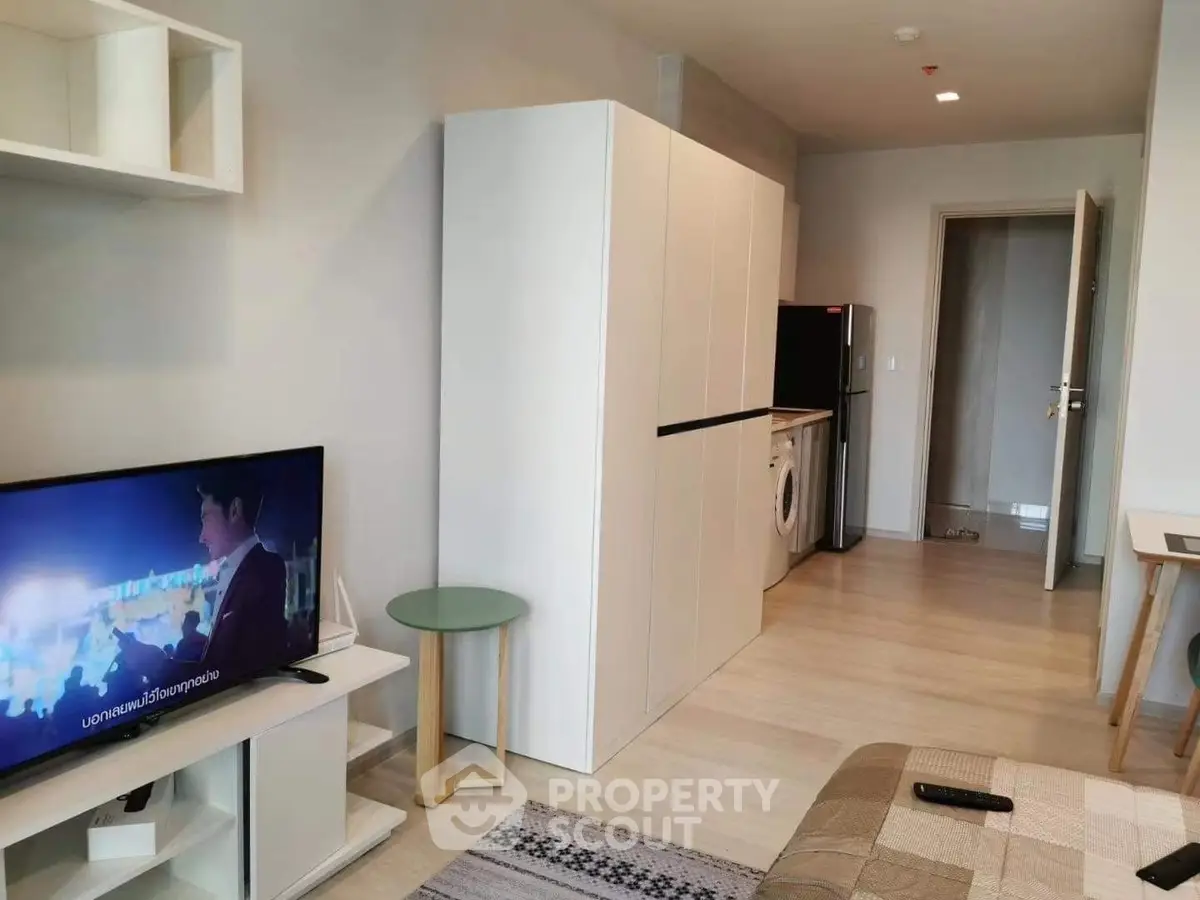 Modern living room with TV, washing machine, and sleek furniture in a cozy apartment.