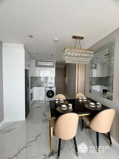 Elegant dining area with modern kitchen featuring marble flooring and chic chandelier