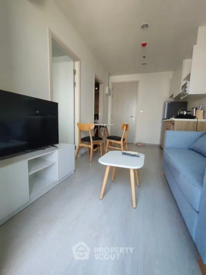Modern living room with sleek furniture and open kitchen layout in a cozy apartment.