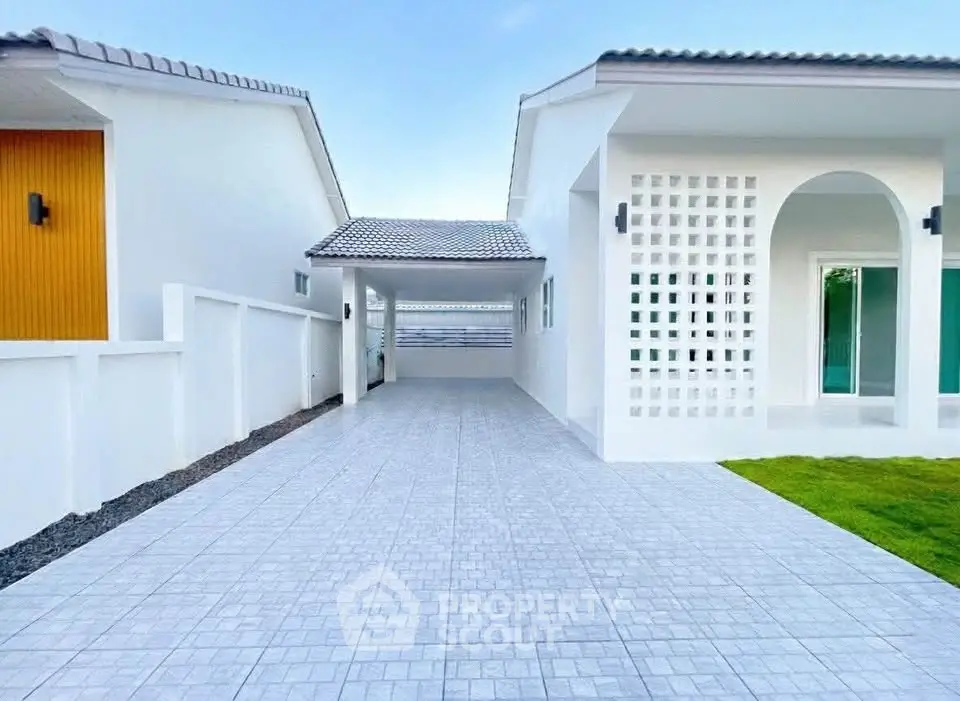Modern white house with spacious driveway and elegant architectural design.