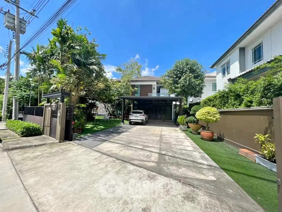 Spacious driveway leading to a modern home with lush greenery and a parked car.