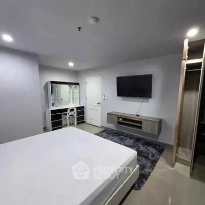 Spacious bedroom with modern furniture and wall-mounted TV in a stylish apartment.