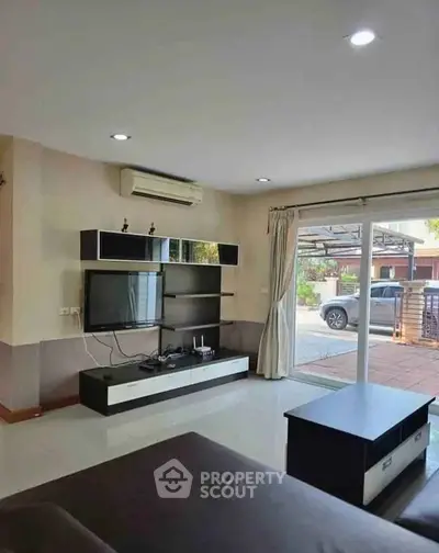 Spacious living room with modern entertainment center and large sliding glass doors to patio.