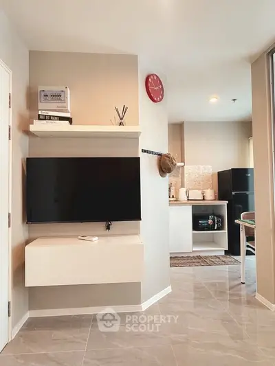 Modern living room with sleek TV setup and open kitchen layout in stylish apartment.