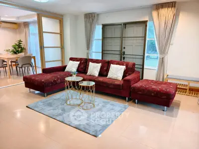 Spacious living room with elegant red sofa and stylish decor, perfect for modern living.