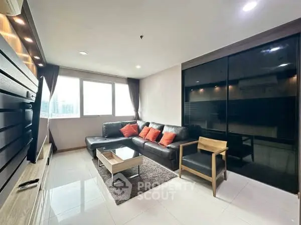Modern living room with sleek furniture and large windows offering city views.