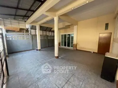 Spacious covered outdoor area with tiled flooring and sliding glass doors.