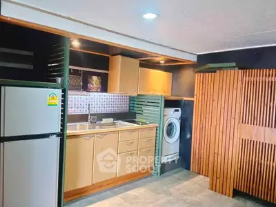 Modern kitchen with wooden cabinets, washing machine, and fridge in stylish apartment.