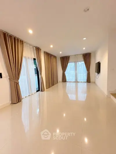 Spacious modern living room with elegant curtains and glossy tiled floor, perfect for stylish living.