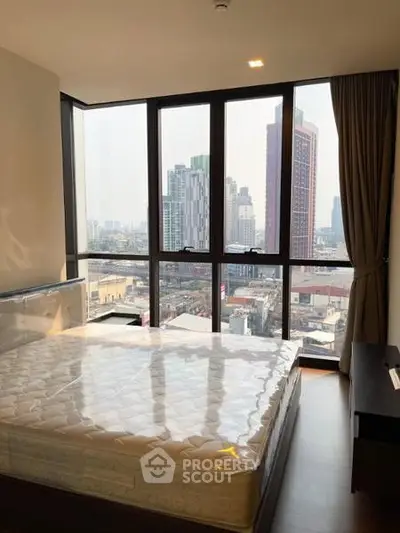 Modern bedroom with large windows offering stunning city views in a high-rise apartment.
