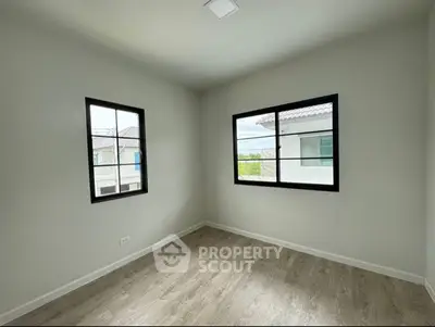 Bright empty room with large windows and wooden flooring, perfect for customization.