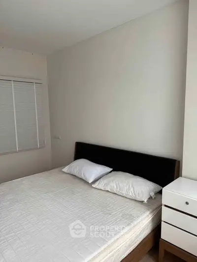 Cozy bedroom with minimalist design featuring a comfortable bed and modern nightstand.
