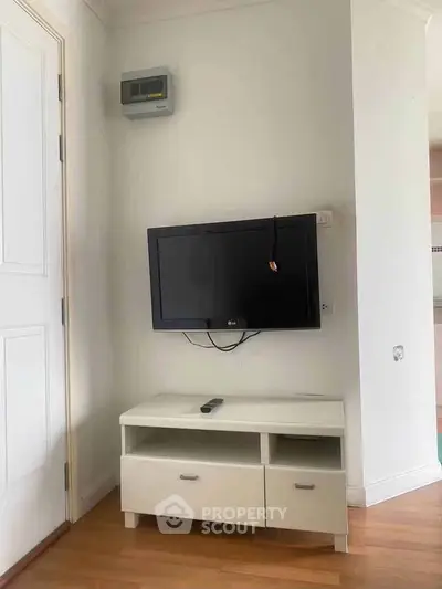 Modern living room corner with wall-mounted TV and sleek white cabinet