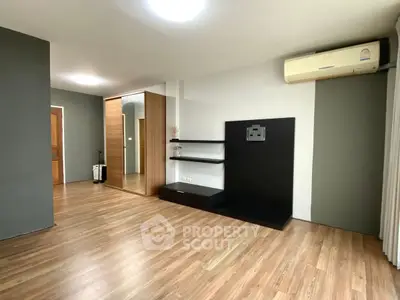Spacious modern living room with wooden flooring and built-in shelves