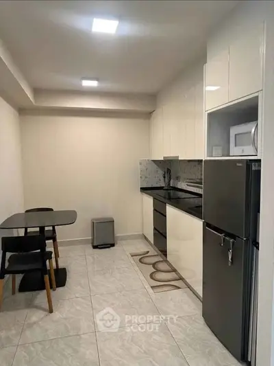 Modern kitchen with sleek black and white design, featuring dining area and stainless steel appliances.