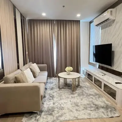Modern living room with cozy sofa, stylish decor, and large TV setup.