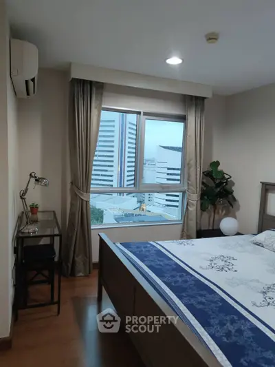 Cozy bedroom with city view, featuring a stylish bed, desk, and large window for natural light.