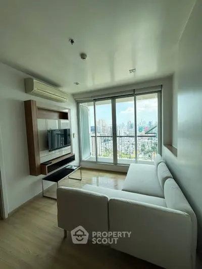 Modern living room with city view, featuring sleek furniture and large windows for natural light.