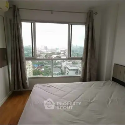 Spacious bedroom with large window offering stunning city view