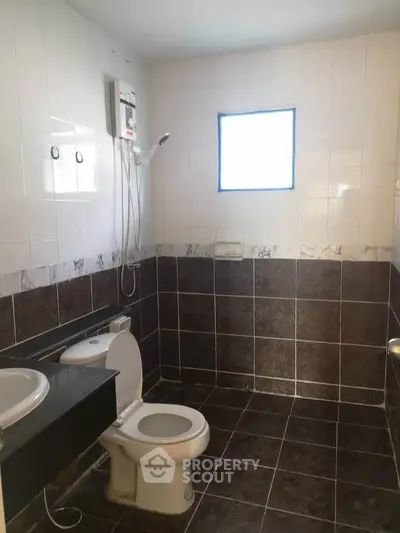 Modern bathroom with tiled walls and floor, featuring a shower and toilet.