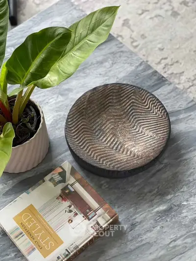 Elegant marble coffee table with decorative plant and stylish book, perfect for modern living room decor.