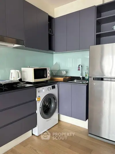 Modern kitchen with sleek cabinets, washing machine, and stainless steel fridge