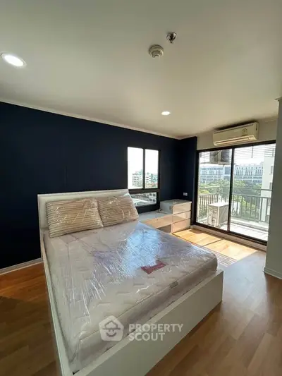 Spacious bedroom with large windows and balcony access in modern apartment.