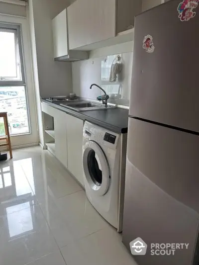 Modern kitchen with washing machine and fridge in bright apartment