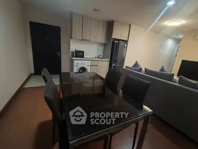 Modern open-plan living room with dining area and kitchen featuring sleek appliances.