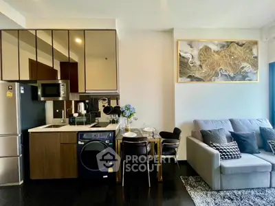 Modern living room with integrated kitchen, featuring sleek appliances and stylish decor.