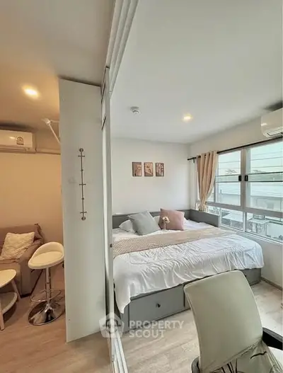 Modern cozy bedroom with large windows and stylish decor in a bright apartment.