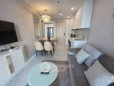 Modern living room with elegant decor, featuring a cozy sofa, dining area, and sleek kitchen appliances.