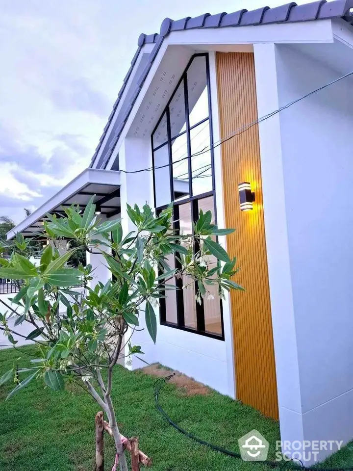 Modern house exterior with large windows and lush green lawn