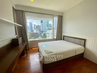 Spacious bedroom with city view, featuring a large window and wooden flooring, perfect for urban living.
