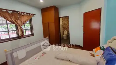 Cozy bedroom with attached bathroom and wooden wardrobe, ideal for comfortable living.