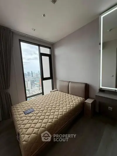 Modern bedroom with city view, featuring a cozy bed and large window for natural light.