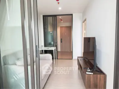 Modern living room with sleek design and glass sliding doors, featuring a cozy sofa and flat-screen TV.
