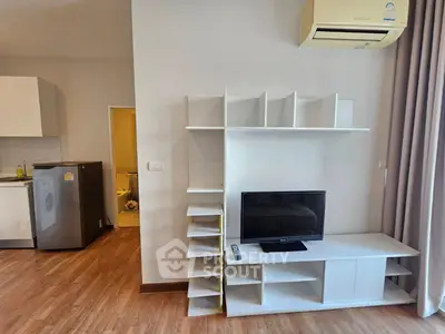 Modern living room with sleek TV stand and air conditioning, adjacent to a compact kitchen with washing machine.