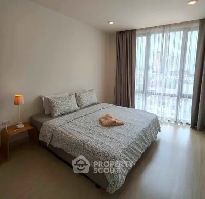 Cozy bedroom with large window offering city views, featuring a comfortable bed and modern decor.