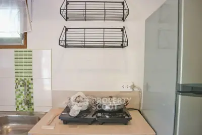 Compact kitchen with dual gas stove and modern fridge, ideal for small apartments.