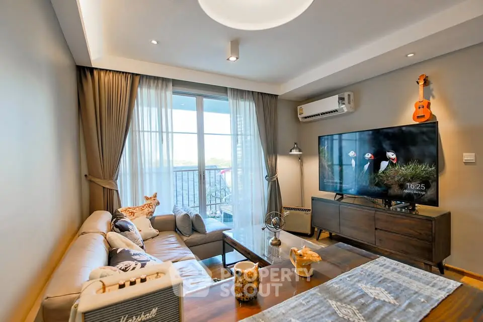 Stylish living room with modern decor, large TV, and balcony access in a cozy apartment.