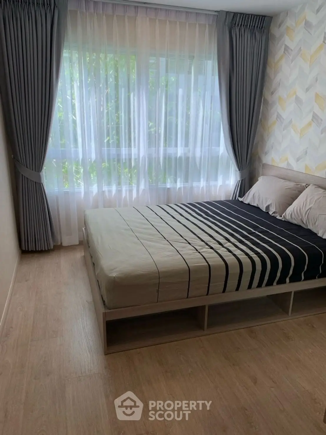 Cozy bedroom with large window and elegant curtains, perfect for natural light lovers.