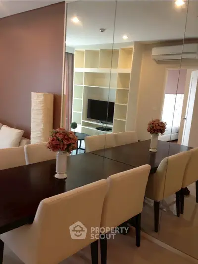 Modern living room with elegant dining area and mirrored wall, featuring cozy seating and stylish decor.