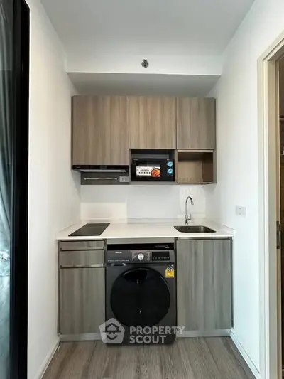 Modern compact kitchen with sleek cabinetry and built-in appliances in a stylish apartment.
