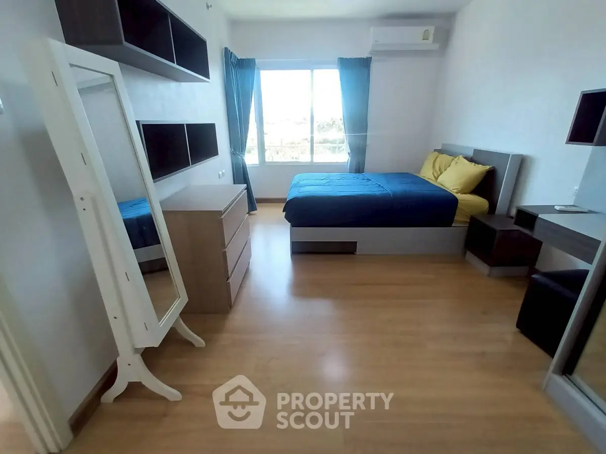 Spacious bedroom with modern furnishings and large window offering natural light.